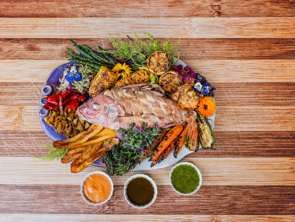 fresh colorful summer entree with grilled fish, fried potatoes, and grilled carrots and corn