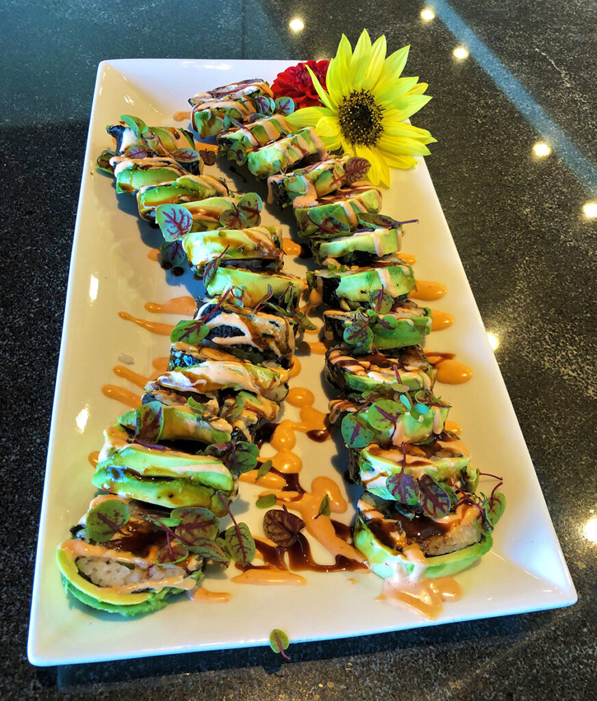 two fresh sushi rolls topped with avocado