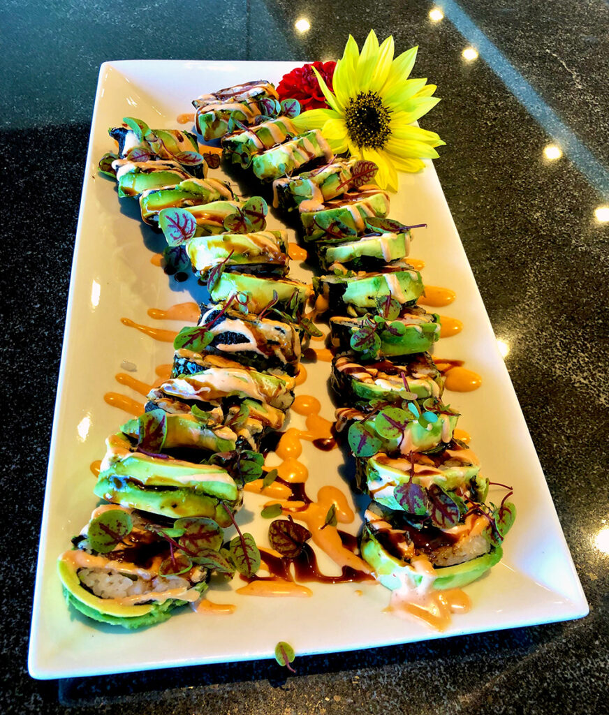 two bright and colorful spicy ahi sushi rolls topped with avocado served as appetizers or entrees